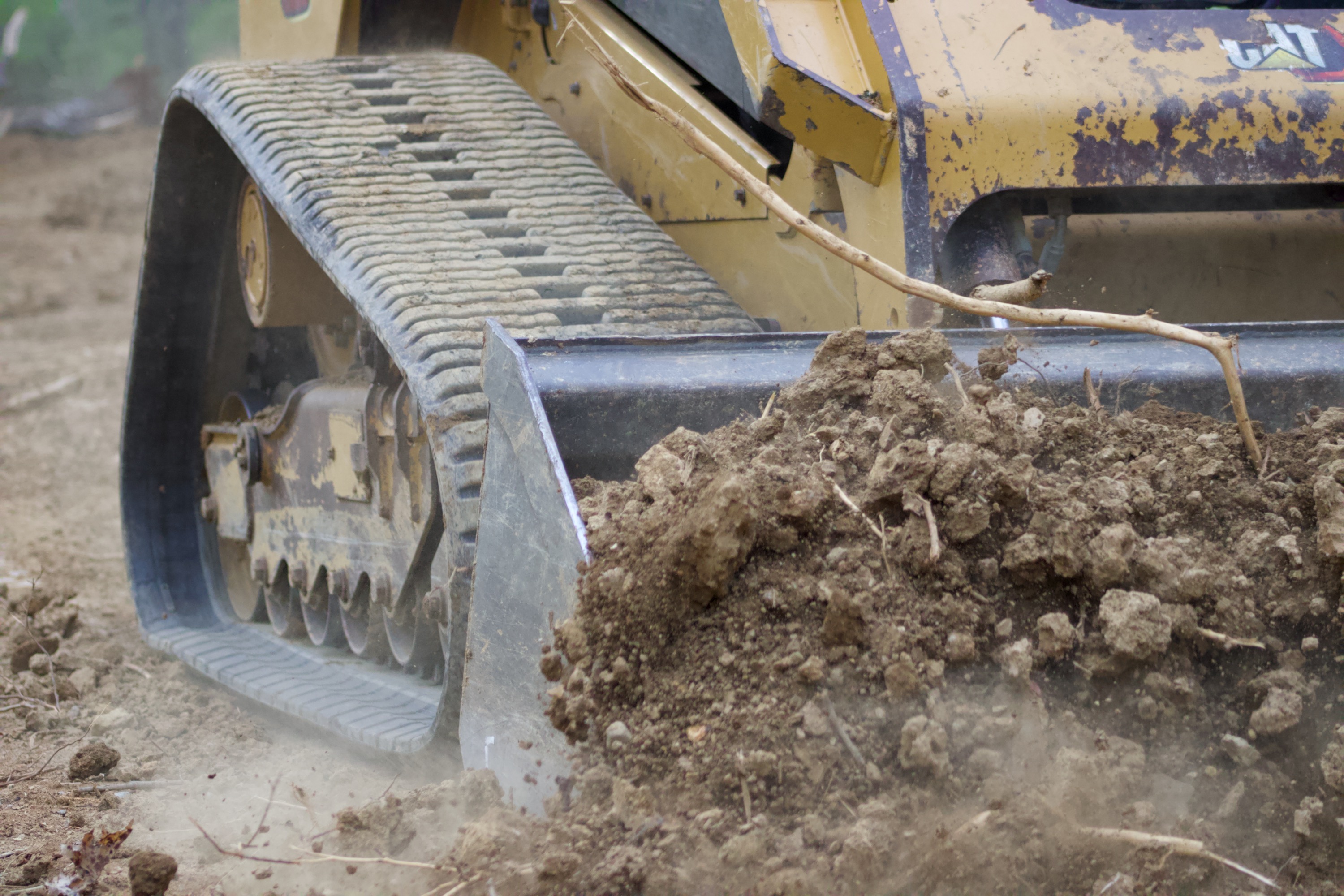 CAT skid steer pushing dirt with blade attachment — land clearing Nashville TN